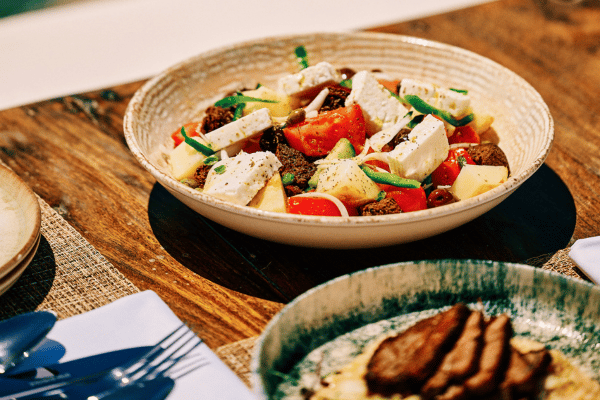 Traditional Greek salad with feta, tomatoes, olives, and green peppers served in a rustic ceramic bowl at Sunsets Terra in Santorini