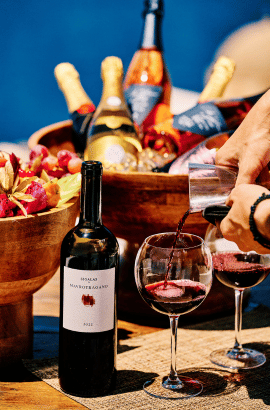 Red wine being poured into glasses next to a bottle of Greek wine and a chilled bowl of champagne at Bites & Bubbles by Sunsets, Santorini