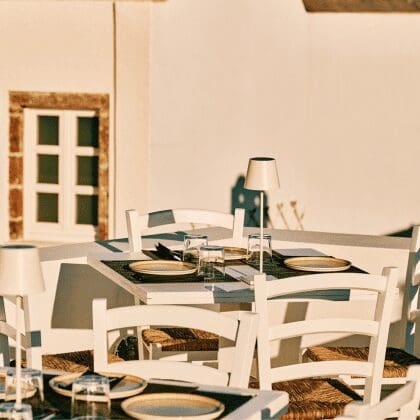 Sunlit terrace setup with white chairs and minimalist table settings at Sunsets Santorini