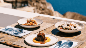 Gourmet lunch at Sunsets Santorini with beef fillet, Greek salad, and pasta served on a terrace overlooking the Aegean