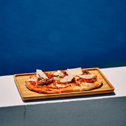 Mediterranean-style flatbread pizza with shaved cheese served cliffside at Bites & Bubbles by Sunsets in Santorini