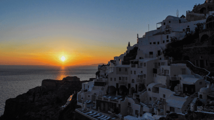 Sunset over the Aegean Sea with silhouetted white Cycladic houses in Oia, Santorini