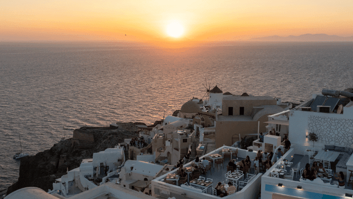 Breathtaking Santorini sunset over the Santorini Sunsets restaurant and neighbouring terraces overlooking the Aegean Sea.