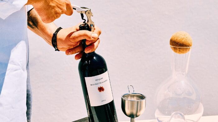 Sommelier opening a bottle of Sigalas Mavrotragano red wine during a tasting session in Santorini.