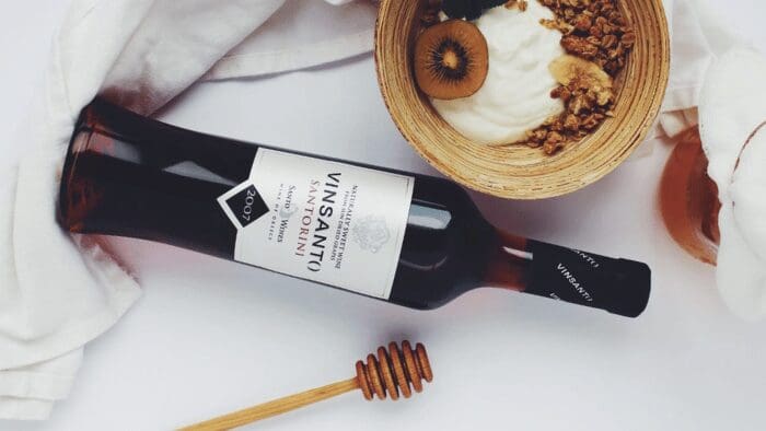 Two glasses of Assyrtiko and Vinsanto wine served with a Mediterranean food platter in Santorini, offering perfect wine pairings.