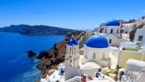 Blue-domed church in Oia, Santorini, Greece overlooking the caldera and Aegean Sea on a clear day.