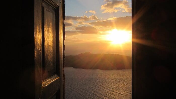 image of santorini sunset through door in Oia