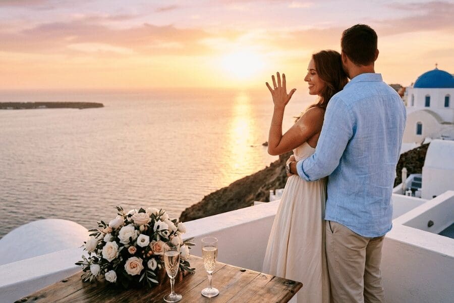 Couple celebrating an engagement on an Oia terrace at sunset, captured by a professional Santorini proposal photographer