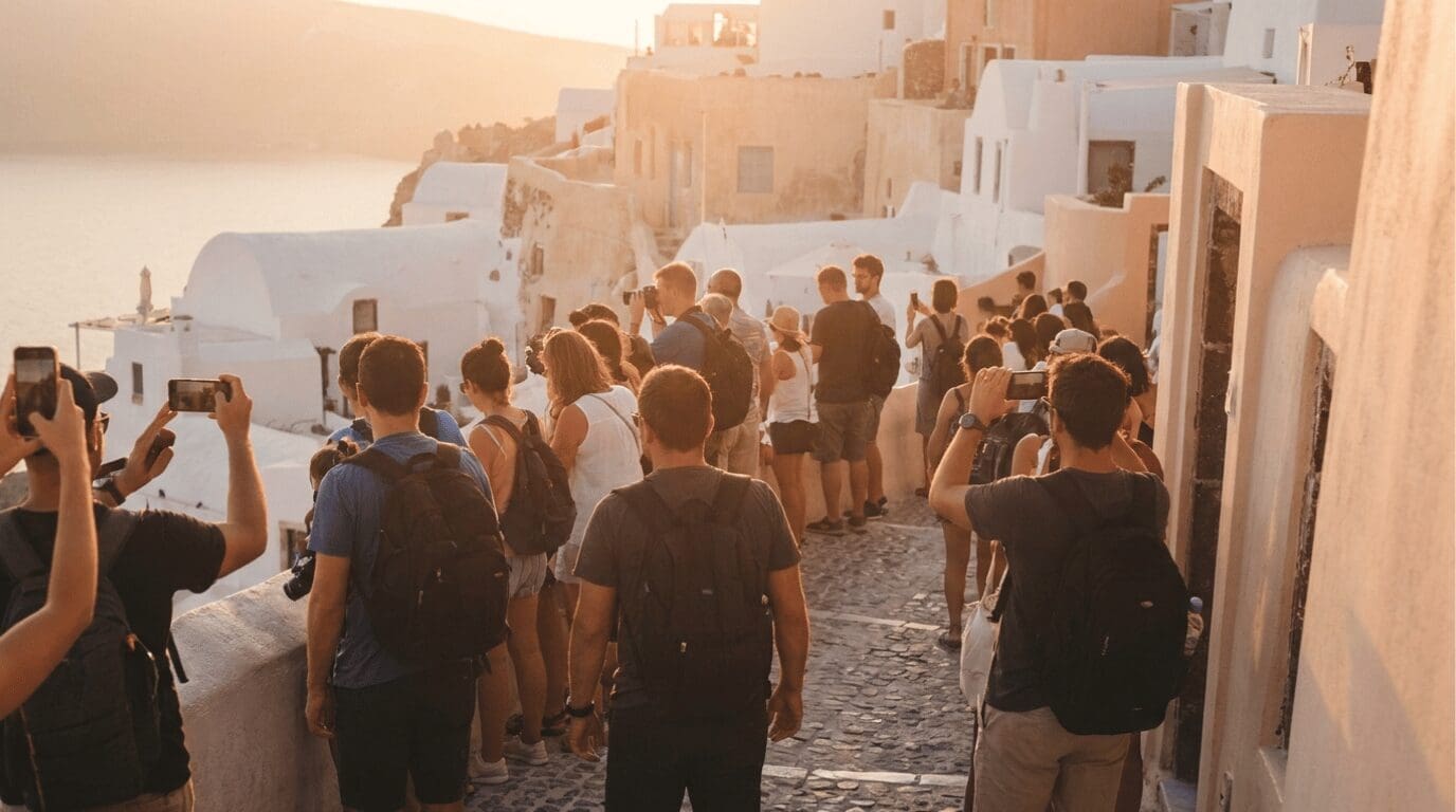Crowds gathered along Oia's caldera walkway at sunset in Santorini, illustrating peak-season visitor density