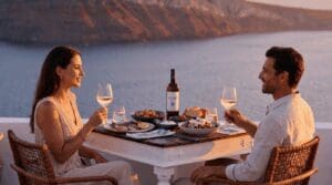 Couple toasting with wine at a sunset dinner table on the caldera terrace at Santorini Sunsets in Oia